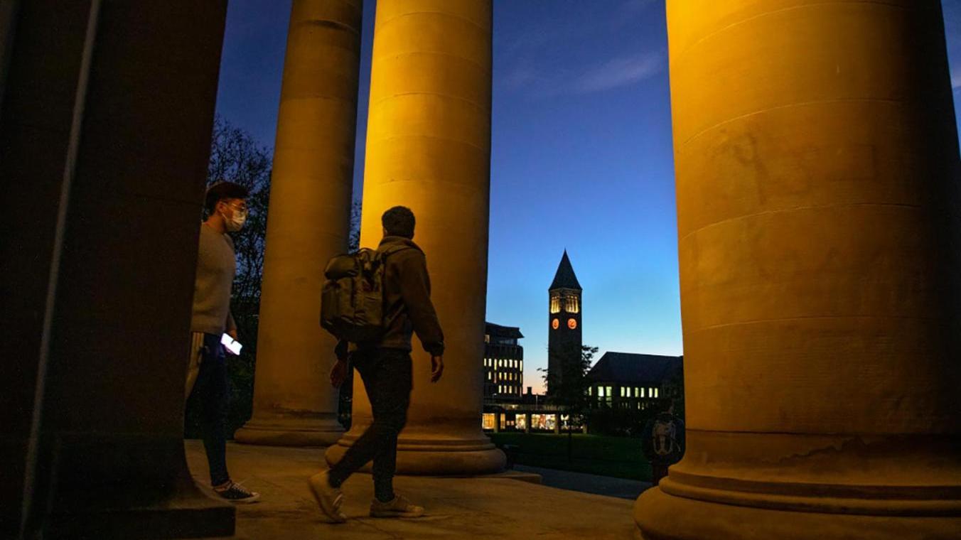 Students leaving Goldwin Smith Hall at dusk